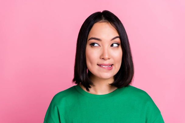 Portrait of minded thai lady biting lip look interested empty space ponder isolated on pink color background. - Foto, Imagen