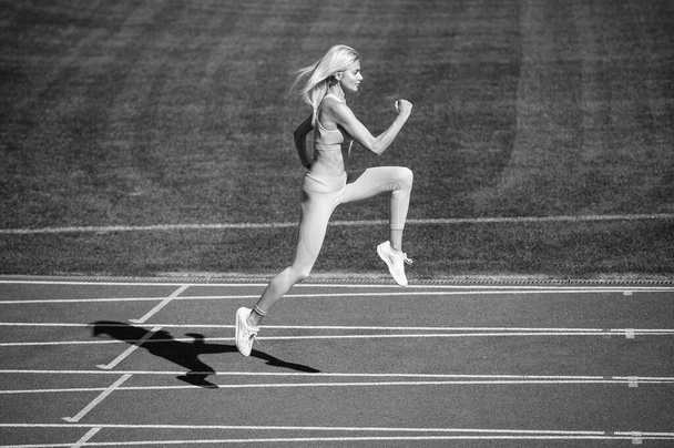 fit lady in fitness wear running on stadium racetrack while sport workout, speed. - Foto, Bild