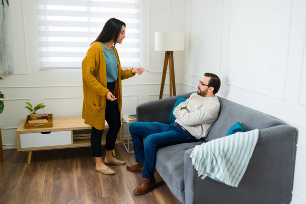Upset latin woman having an argument with an upset caucasian man at home talking about breaking up or divorce - Photo, Image