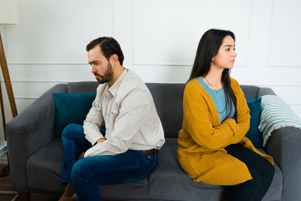 Trauriges aufgebrachtes Paar, das schweigend ihre Probleme ignoriert, wenn es nach einem Kampf mit dem Rücken zueinander auf der Couch sitzt - Foto, Bild