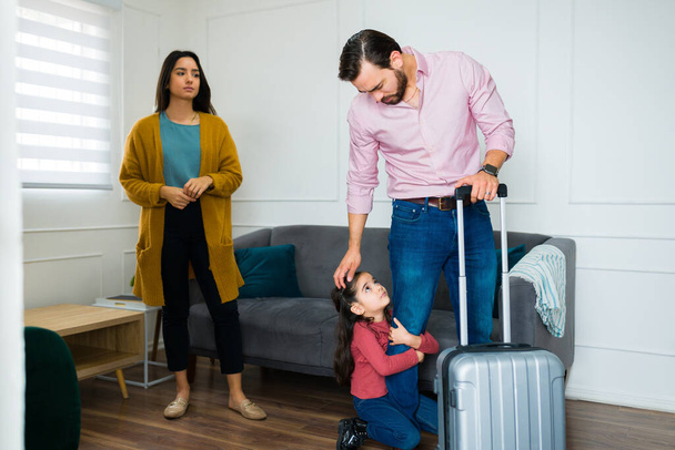 Rodina rozvrácena kvůli rozvodu, zatímco malé dítě objímající nohu svého otce, zatímco opouští domov a prosí, aby zůstali doma  - Fotografie, Obrázek