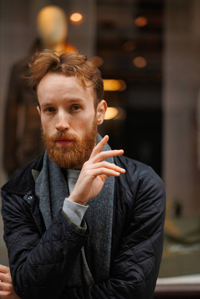 Portrait of a stylish bearded man against the backdrop of a clothing store window - Foto, afbeelding