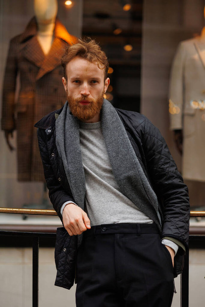 Portrait of a stylish bearded man against the background of elegant clothing store window - 写真・画像