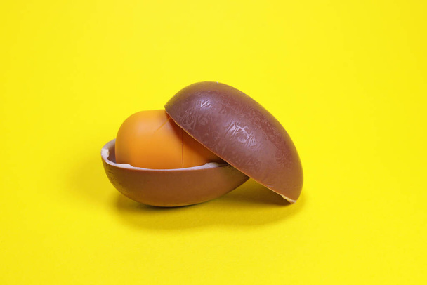 Magdalinovka, Ukraine - March 4, 2023. Kinder surprise chocolate egg by Ferrero open on a yellow background - Zdjęcie, obraz