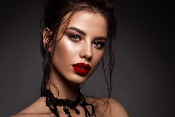 Gorgeous Young Brunette Woman face portrait. Beauty Model Girl with bright eyebrows, perfect make-up, red lips, touching her face. Sexy lady makeup for party. - Photo, Image