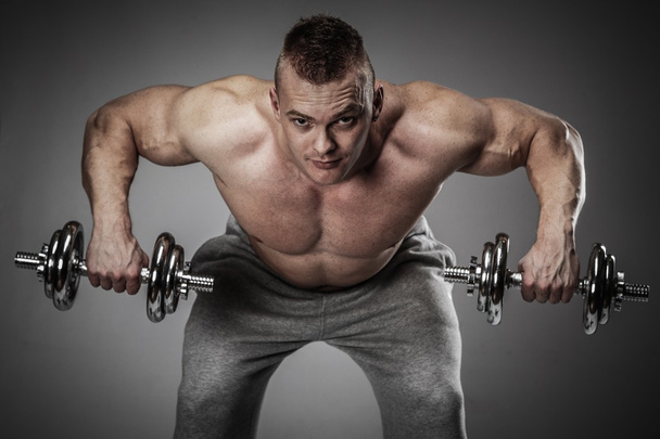 Muscular man exercising with dumbbells - Photo, Image