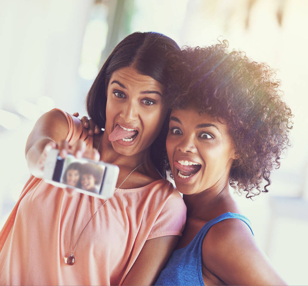 Les moments amusants font les meilleurs souvenirs. deux copines prenant un selfie sur un téléphone portable - Photo, image