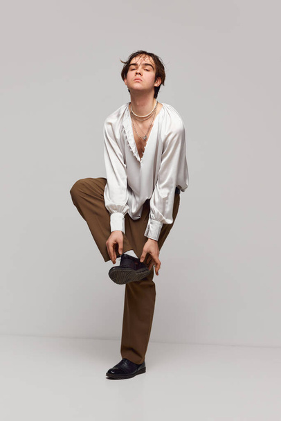 Fashion portrait of stylish high fashionable boy posing isolated over grey background. Masculinity and femininity. Concept of modern fashion, uniqueness, ad - Foto, afbeelding