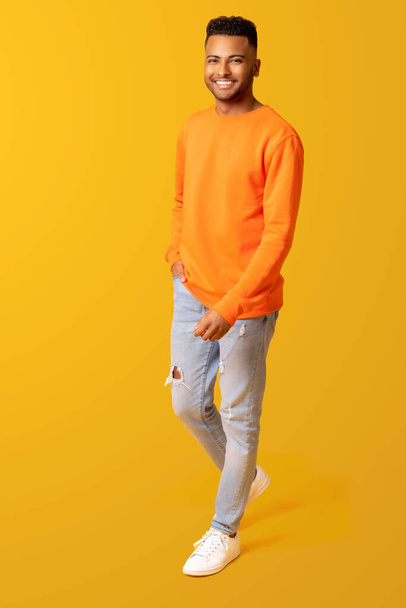 Full length photo of young smiling happy indian 20s man in casual wear isolated on plain yellow color, handsome arab man walking and looking at the camera with attractive smile - Foto, immagini