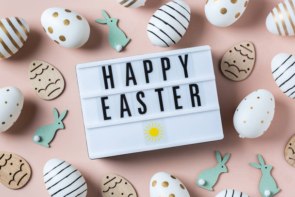 Happy Easter frame with golden, white, black dotted and striped eggs on a pink background. Top view, flat lay. Modern Easter greeting card - Photo, Image