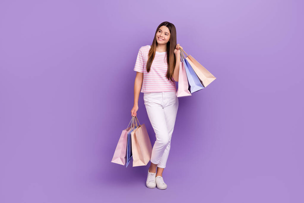 Full length portrait of cheerful nice girl hold store mall bags look empty space isolated on purple color background. - Foto, Bild