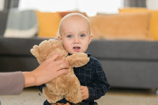 Счастливый мальчик играет со своим плюшевым медведем дома - этапы детства и развития ребенка - Фото, изображение
