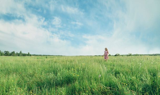 Tyttö kävelee kesäniityllä
 - Valokuva, kuva