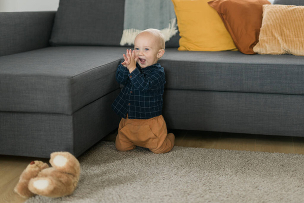 Surprised baby sitting on carpet. Childs eyes widened and mouth opened in amazement. Copy space for text concept - Fotó, kép