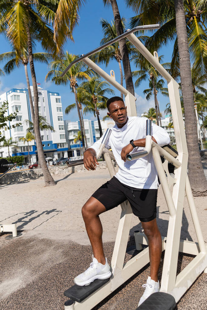 full length of african american sportsman working out on outdoor gym equipment in Miami beach  - Foto, Imagem