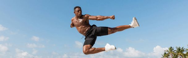 muscular african american man jumping while working out in Miami beach, banner  - Foto, afbeelding