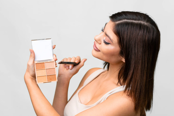 jonge Russische vrouw over geïsoleerde witte achtergrond met make-up palet - Foto, afbeelding