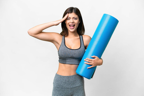 Young sport woman going to yoga classes while holding a mat over isolated white background with surprise expression - Valokuva, kuva
