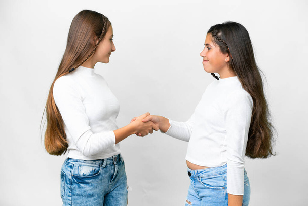 Friends girls over isolated white background handshaking after good deal - 写真・画像