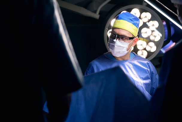 Cirurgião experiente no local de trabalho na sala de cirurgia, dentro de casa com uma lâmpada poderosa - Foto, Imagem