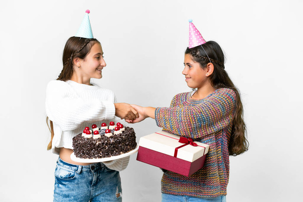 Amigos niñas sosteniendo regalo y un pastel de cumpleaños sobre fondo blanco aislado apretón de manos después de un buen trato - Foto, imagen
