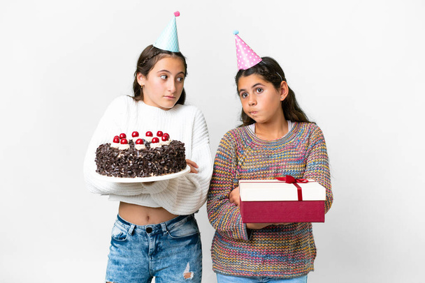 Arkadaşlar hediye alır ve beyaz arka planda doğum günü pastası yapar. Omuzlarını kaldırırken şüphe duyarlar. - Fotoğraf, Görsel