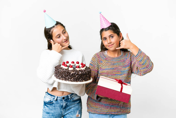 Friends girls holding gift and a birthday cake over isolated white background making phone gesture. Call me back sign - Photo, image