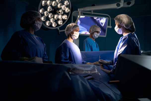 麻酔下の男性は手術台の上にあり、手術チームによって運営されています。 - 写真・画像