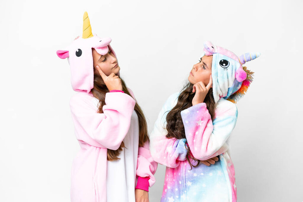 Přátelé dívky s jednorožec pyžama přes izolované bílé pozadí myšlení nápad při škrábání hlavy - Fotografie, Obrázek