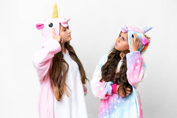Přátelé dívky s jednorožec pyžama přes izolované bílé pozadí s pochybnostmi při škrábání hlavy - Fotografie, Obrázek