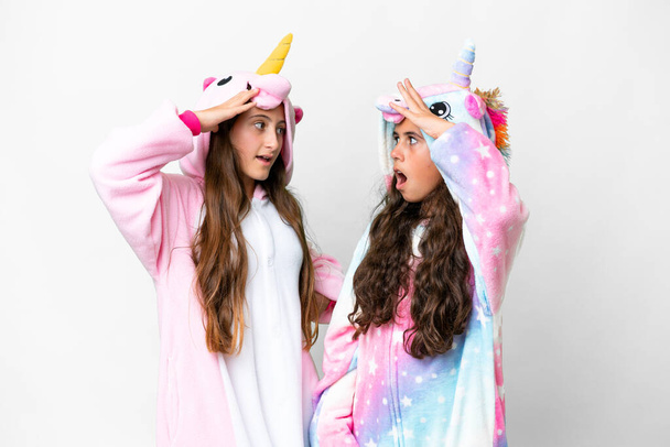 Přátelé dívky s jednorožec pyžama přes izolované bílé pozadí s překvapením a šokovaný výraz obličeje - Fotografie, Obrázek