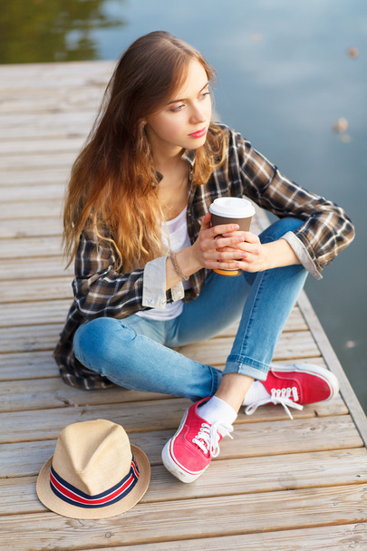 Молода красива дівчина сидить на пірсі
 - Фото, зображення