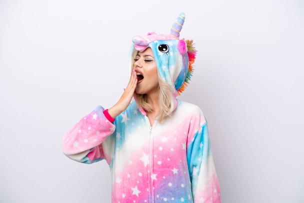 Young Russian woman with unicorn pajamas isolated on white background yawning and covering wide open mouth with hand - Valokuva, kuva