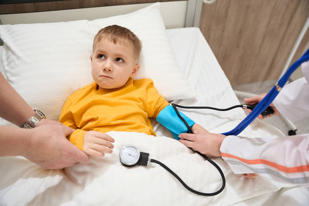 Läheltä katsottuna muotokuva vakavasti pieni poika sairassängyllä on saada pätevää palvelua nykyaikaisessa klinikalla - Valokuva, kuva
