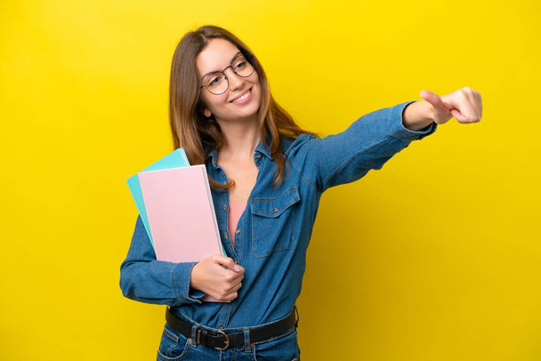 Young student caucasian woman isolated on yellow background giving a thumbs up gesture - Photo, Image