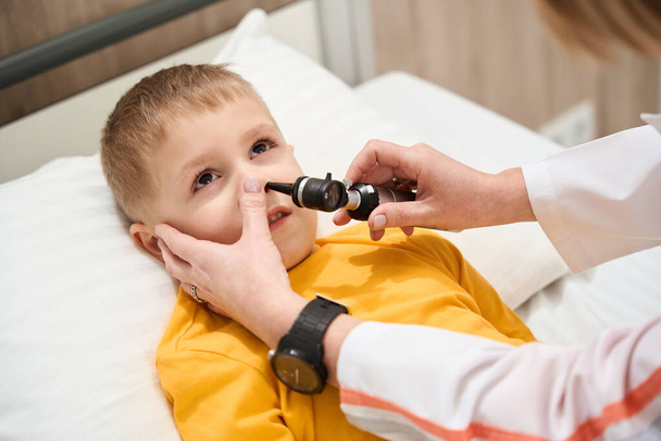 Крупным планом портрет аккуратного мальчика проходит обследование здоровья со специальным оборудованием в лечебной клинике - Фото, изображение