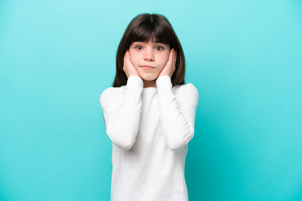Little caucasian girl isolated on blue background frustrated and covering ears - Φωτογραφία, εικόνα