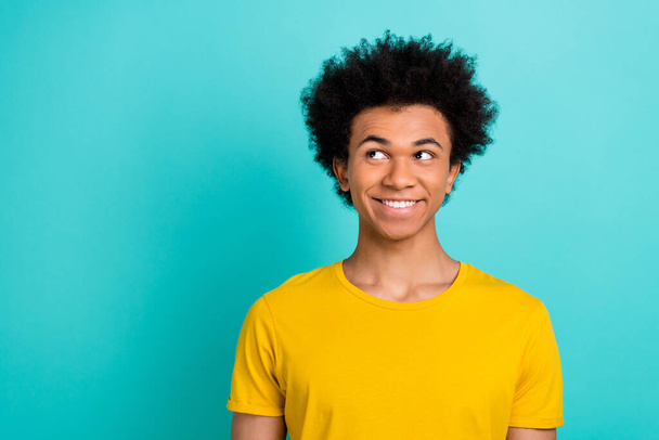 Portrait of friendly good mood guy with afro hairdo wear yellow t-shirt look at sale empty space isolated on shine teal color background. - Φωτογραφία, εικόνα