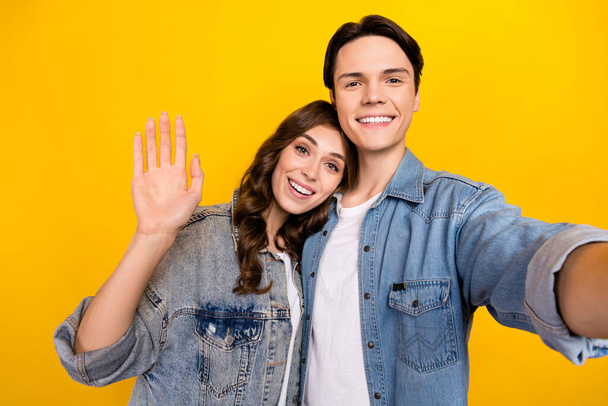 Photo of attractive girl handsome man take selfie record video arm palm waving hi isolated on yellow color background. - Foto, immagini