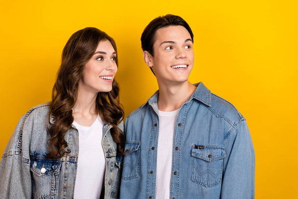 Photo of two positive cheerful people beaming smile look interested empty space isolated on yellow color background. - Zdjęcie, obraz
