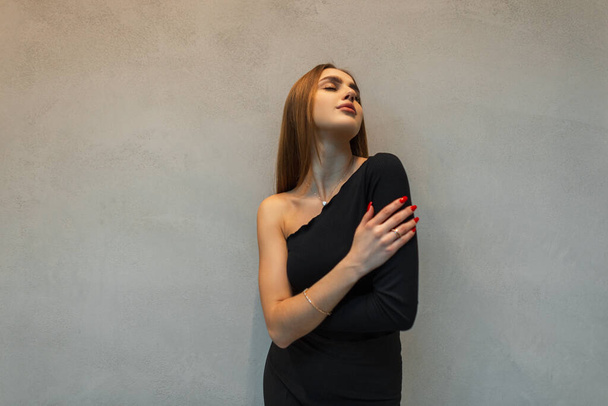 Κομψό όμορφη επιτυχημένη επιχειρηματίας κυρία στη μόδα μαύρα ρούχα με μια κορυφή και παντελόνι θέτει κοντά στο γκρίζο τοίχο - Φωτογραφία, εικόνα