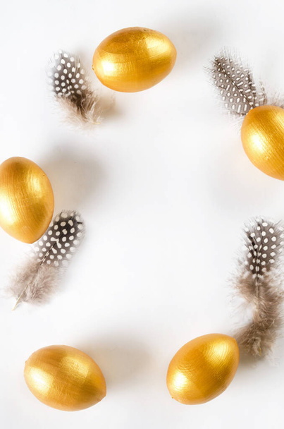 Decorative golden eggs and feathers on white background. Happy Easter minimal concept. Flat lay trendy easter. Happy easter card. Copy space for text. - Foto, Imagem