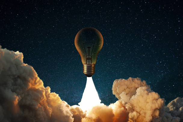 Creative rocket light bulb with smoke and blast successfully takes off into the starry sky. Business start up launch and successful idea, concept. - Φωτογραφία, εικόνα