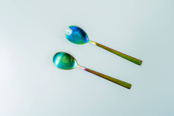 Set of iridescent metal salad spoons on a smooth surface - Photo, Image