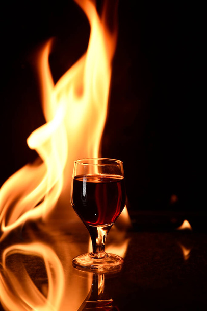 chupito de bebida de coñac con fuego en el vaso de fondo de vino tinto - Foto, imagen