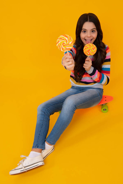 Tinédzser lány karamellás cukorkával, cukorfüggőséggel. Nyalókás gyerek. Boldog tinédzser, pozitív és mosolygós érzelmek tini lány - Fotó, kép