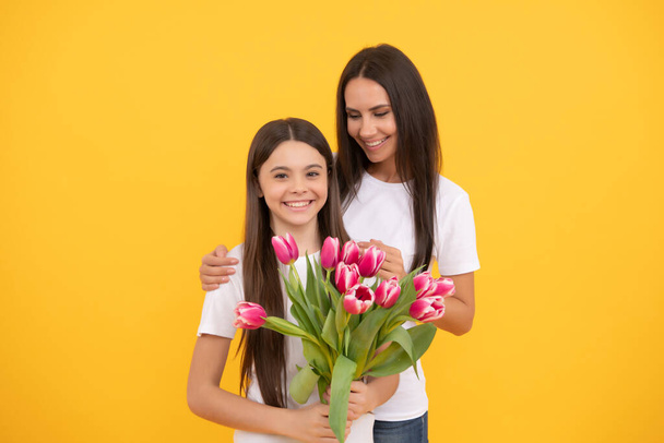 幸せな母親と娘とともに春のチューリップを黄色の背景に. - 写真・画像