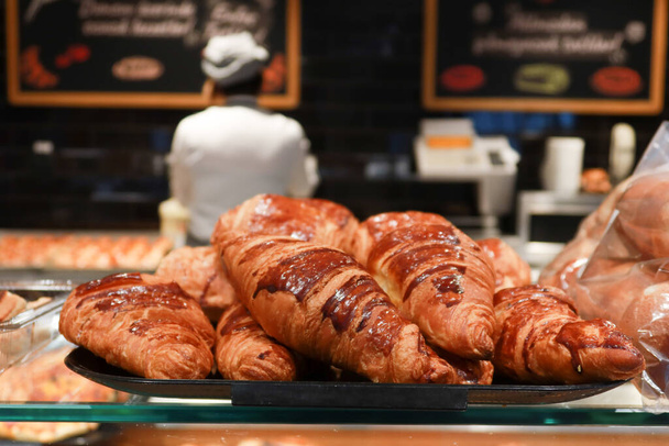 fresh baked croissant piled up on table against cafe background . - Фото, изображение