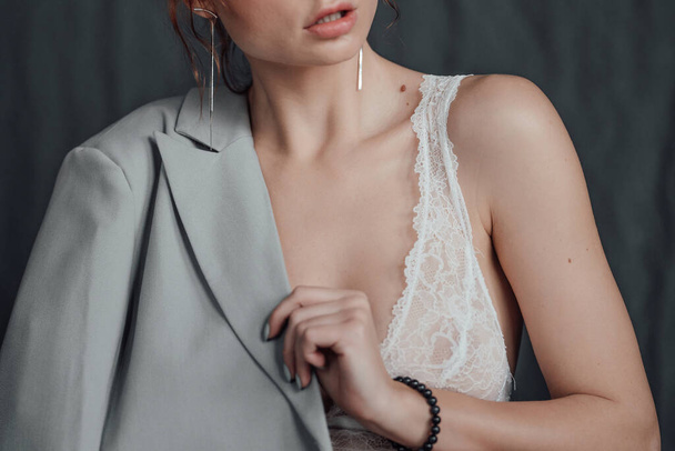 Adult beauty elegant young woman in formal evening gray suit with white bra at thoughtful. Stylish ginger curly hair sensual model bare shoulder fashionista posing at studio in fashion pantsuit - Fotó, kép