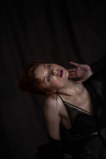 Adult beauty elegant young woman in formal evening black clothing hand on face touching. Stylish ginger curly hair sensual model bare shoulder fashionista posing at studio in fashion pantsuit and bra - Foto, imagen
